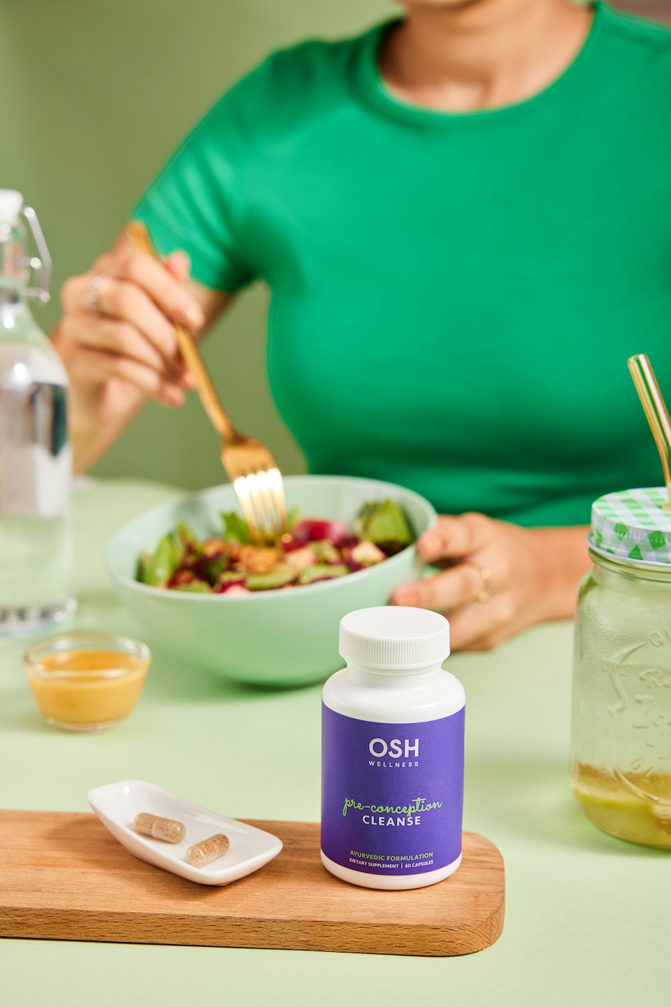 Person isst Salat neben OSH Wellness Produkten.