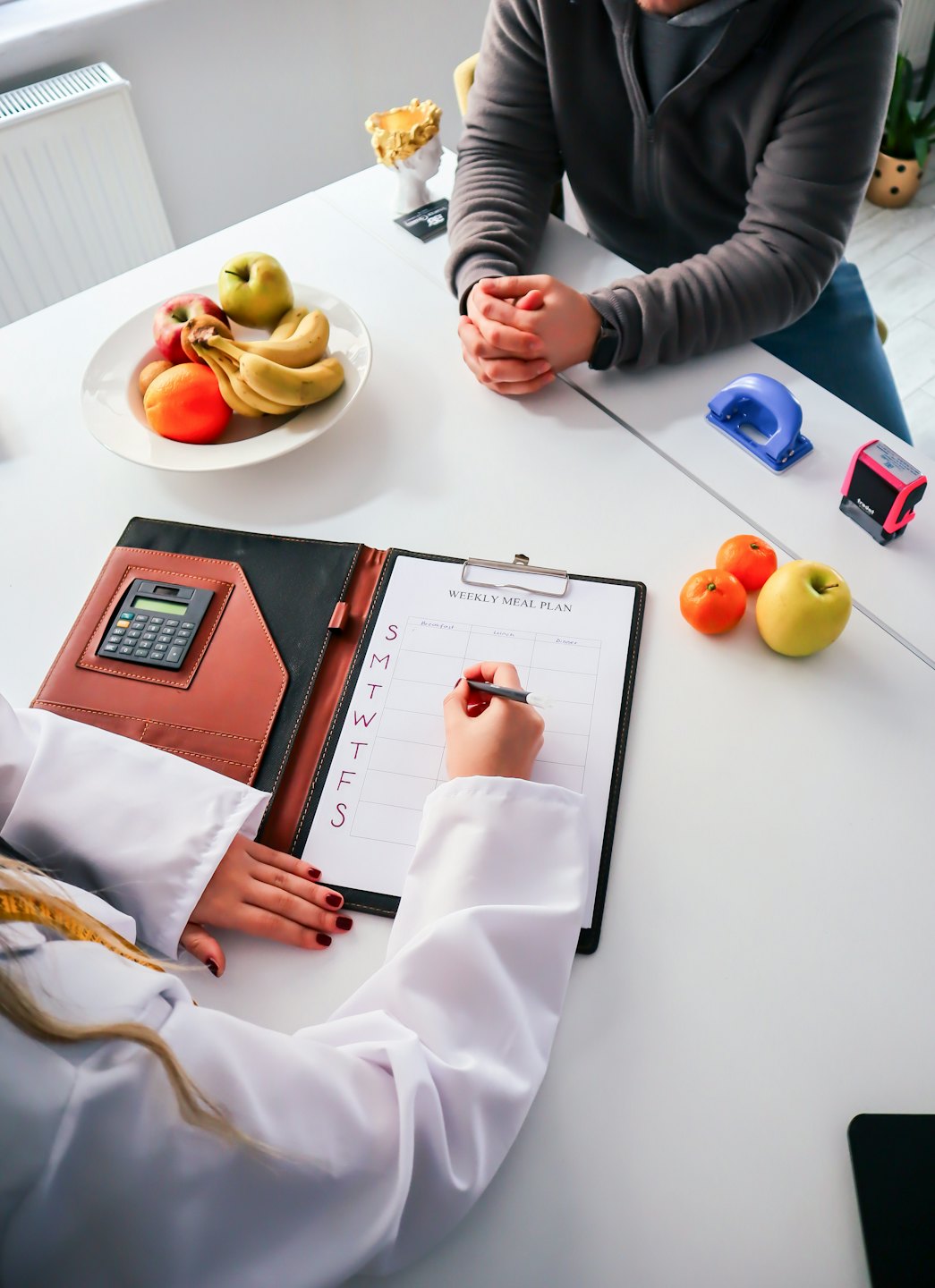 Ernährungsberaterin bespricht mit Klientin einen Ernährungsplan und Obst.